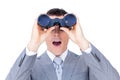 Surprised businessman looking through binoculars