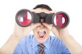 Surprised businessman looks through binoculars