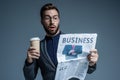 Surprised businessman in suit and glasses holding a paper cup and reading business newspaper Royalty Free Stock Photo