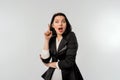 Surprised businesswoman with dark hair looking into the camera and she has an idea. Career girl keeps finger up. Eureka gesture. Royalty Free Stock Photo