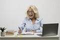 Surprised businesswoman working on laptop and taking notes in notebook, surprisingly reading her notations at workplace Royalty Free Stock Photo