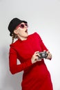 Surprised Caucasian Blond Girl With Old School Film Camera in Red Dress with Sunglasses. Taking Pictures Against White Royalty Free Stock Photo