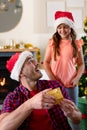 Surprised caucasian father wearing santa hat receiving present from his daughter at christmas time Royalty Free Stock Photo