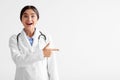 Surprised cheerful young indian woman in white coat with open mouth shows finger to empty space