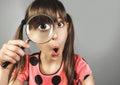 Surprised child girl, searching with magnifying glass