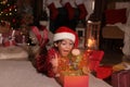Surprised child in Santa hat opening Christmas gift on floor at home Royalty Free Stock Photo