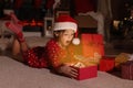 Surprised child in Santa hat opening Christmas gift on floor at home Royalty Free Stock Photo