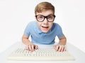 Surprised Child using Computer Keyboard. Teenage Boy Hacker typing on Laptop. Funny Kid In Eye Glasses Study Programming Code