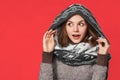 Surprised christmas girl wearing knitted wear scarf. Excited beautiful smiling girl, winter concept, isolated over red background
