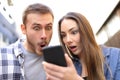 Surprised couple checking online news on smart phone