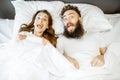 Surprised couple under the bedsheets