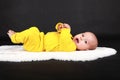 Surprised and curious baby boy lying on back on white fur