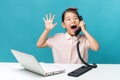 surprised, Cute asia little girl is sitting at table with her white laptop and a telephone, isolated over blue Royalty Free Stock Photo