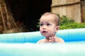 Surprised cute baby boy in blue inflating pool Royalty Free Stock Photo