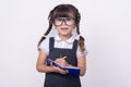 Surprised cute child in eyeglasses writing in notebook using pencil. Five or six years old school kid, on white