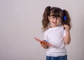 Surprised cute child in eyeglasses, writing in notebook using pencil, keeping mouth wide open. Four or five years, isolated