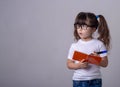 Surprised cute child writing in notebook using pencil, keeping mouth wide open. Four or five years old kid, isolated