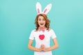 surprised easter girl wear bunny ears hold heart lollipop