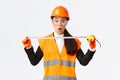 Surprised and excited asian female construction engineer, industrial worker in safety helmet and uniform, measuring Royalty Free Stock Photo