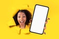 Surprised and excited woman with curly hair looking through a yellow torn paper Royalty Free Stock Photo