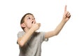 Surprised fair-haired boy in a gray T-shirt stands and points with the index fingers up. Isolate on white background