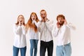 Surprised family, redheaded young men, woman and kid wearing casual style clothes spend time together at studio photo Royalty Free Stock Photo