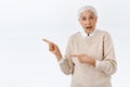 Surprised, fascinated senior woman overreacting, asking question about interesting product, pointing left, open mouth