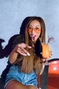 surprised fashionable mulatto girl holding cocktail and pointing