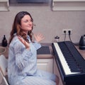 A surprised female pianist in a blue nightgown raised her hands at the piano