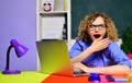 Surprised female teacher in glasses sitting at desk working with laptop in classroom. Student girl studying online. E Royalty Free Stock Photo