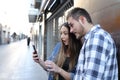 Surprised friends checking smart phone in the street