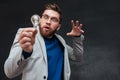 Surprised funnny bearded man in eyeglasses lights the bulb