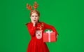Surprised funny child girl in   Christmas reindeer costume with big gift on green background Royalty Free Stock Photo