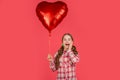 surprised girl hold love heart balloon on red background Royalty Free Stock Photo