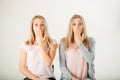 Surprised girl looking at her sister twin over white background