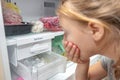 A surprised girl looks at the full ice cube tray of the freezer ice maker Royalty Free Stock Photo