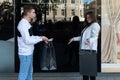Surprised girl meets guy with black bags. Girl is outraged by purchases of her boyfriend. Young couple while shopping