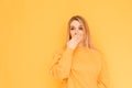Surprised girl in orange clothes stands on a yellow background, looking sideways, shook hands with her face. Isolated Copy space Royalty Free Stock Photo