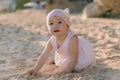 Surprised girl in outdoor with sunset light. Baby in pink dress on sandy beach Royalty Free Stock Photo