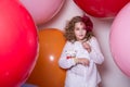 Surprised girl with a soft toy surrounded by huge balloons