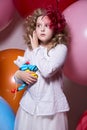 Surprised girl with a soft toy surrounded by huge balloons