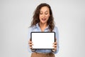 Surprised glad caucasian millennial businesswoman show tablet with blank screen