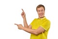 Surprised guy with funny face in yellow Polo T-shirt pointing finger to left, white background Royalty Free Stock Photo