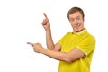 Surprised guy with funny face in yellow Polo T-shirt pointing finger to left, white background Royalty Free Stock Photo