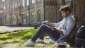 Surprised guy sitting under tree, using mobile phone, reacting to newsfeed