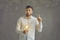 Surprised man thinking and holding glowing lightbulb has bright idea studio shot Royalty Free Stock Photo