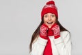 Surprised happy beautiful woman looking sideways in excitement. Christmas girl wearing knitted warm hat and mittens, isolated on g