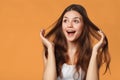 Surprised happy beautiful woman looking sideways in excitement. Isolated on orange background Royalty Free Stock Photo