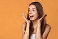 Surprised happy beautiful woman looking sideways in excitement. Isolated on orange background Royalty Free Stock Photo