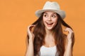 Surprised happy beautiful woman looking sideways in excitement, isolated on orange background